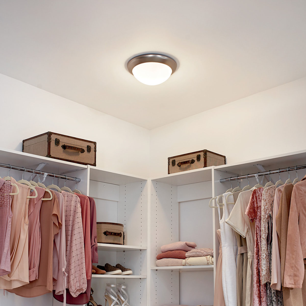 Small corner closet organization with white shelving, hanging clothes, folded sweaters, and storage boxes
