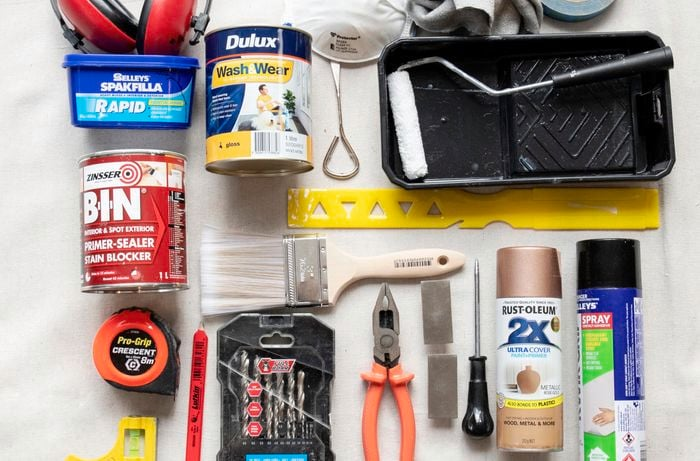 A top down view of a few upcycling tools from paint to measuring all laying on a white ground.