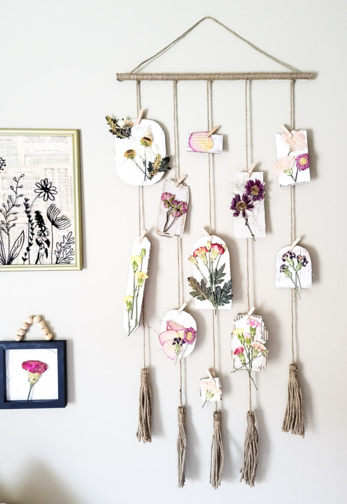 DIY hanging wall display with pressed flowers clipped on string for creative boho room decor