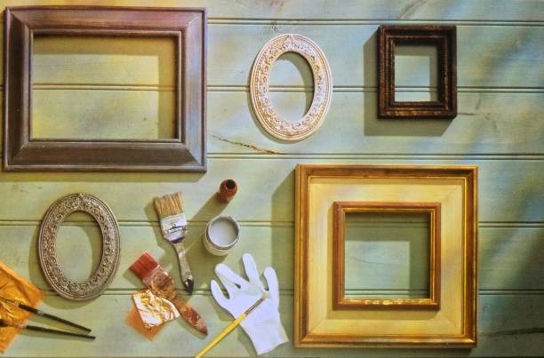 Vintage picture frames with paint brushes and DIY tools laid out for upcycled wall art project