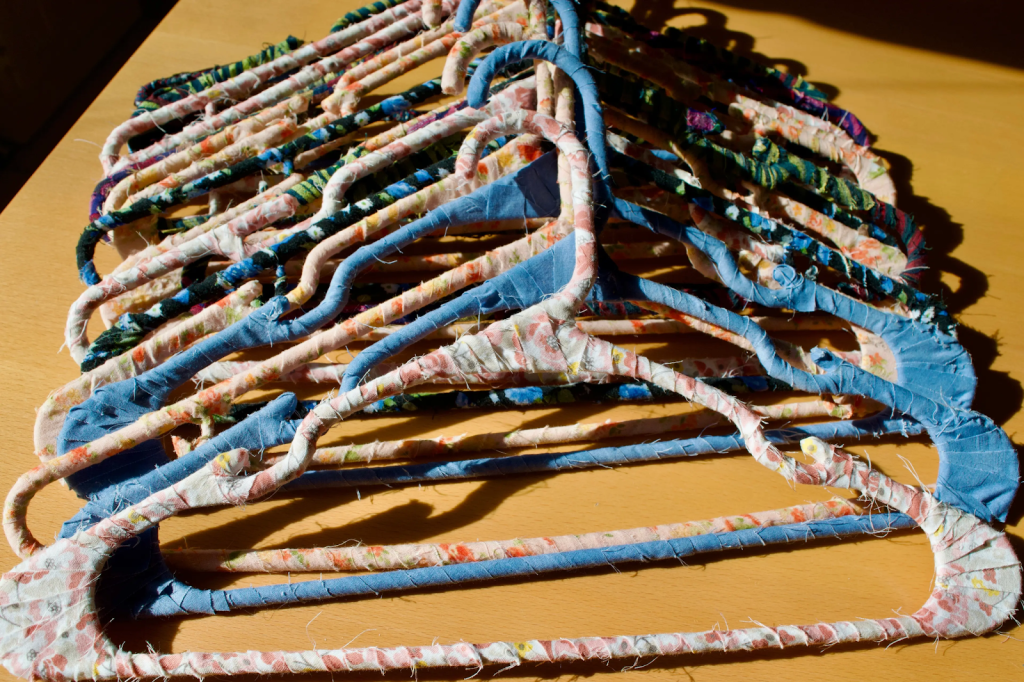 DIY fabric-wrapped wire hangers made from recycled clothing scraps in assorted colors