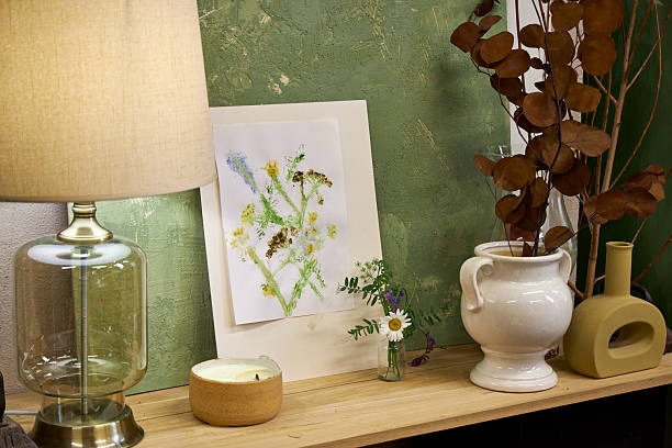 Cozy shelf décor featuring framed botanical artwork, table lamp, candles, and ceramic vases