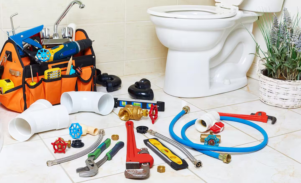 Bathroom plumbing tools and supplies laid out near toilet for repair and installation work