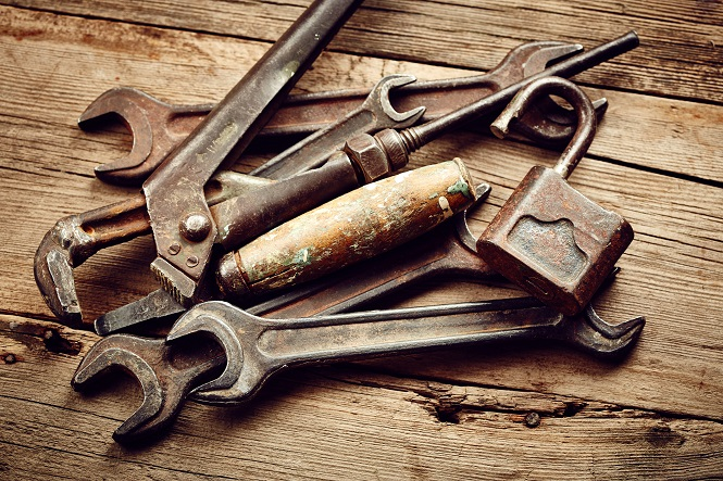 Top down closeup view of a pile of rusty tools on a wooden background.
