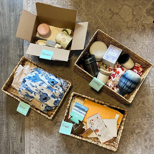 Decluttering items sorted into keep, donate, storage, and trash baskets