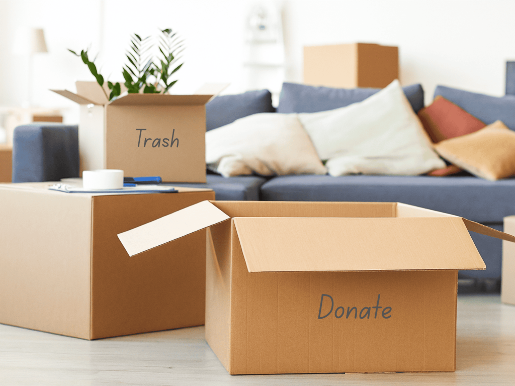 Decluttering room with labeled donate and trash moving boxes