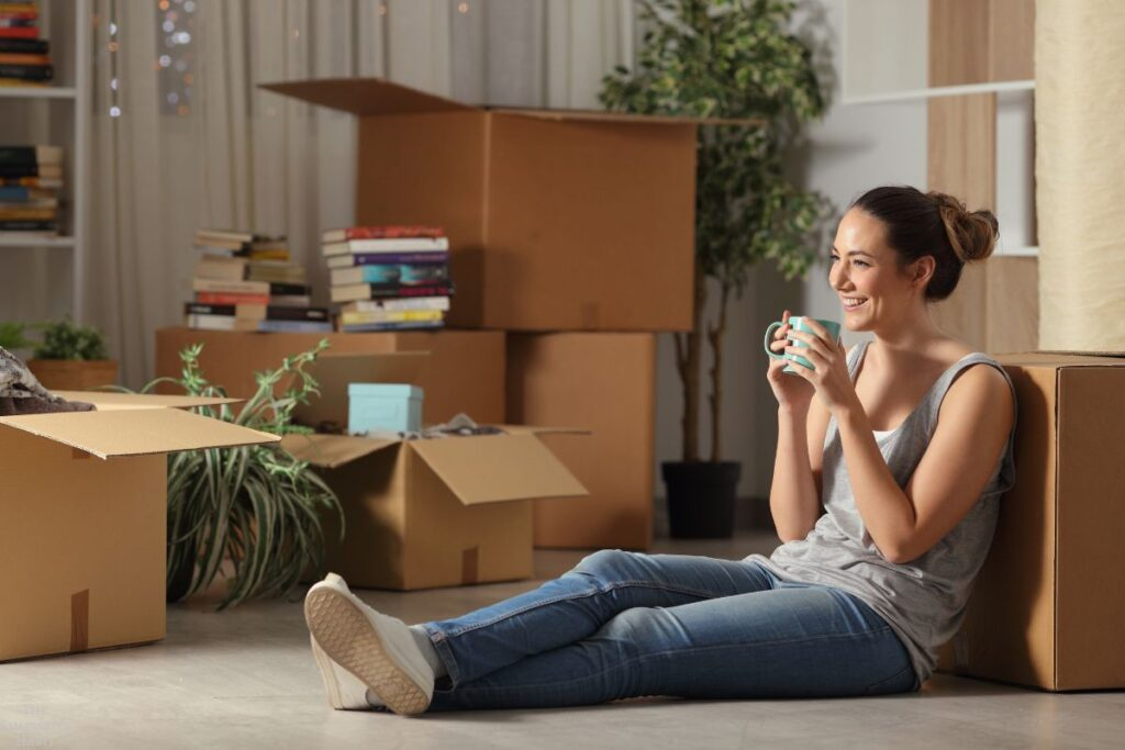 Woman relaxing after decluttering home surrounded by packed moving boxes