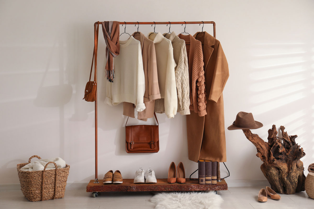 Stylish open clothing rack with neutral outfits, handbags, shoes, and decorative storage