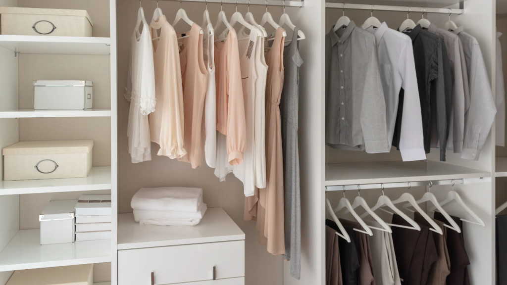 Minimalist wardrobe closet with neutral clothing, open shelves, and folded linens