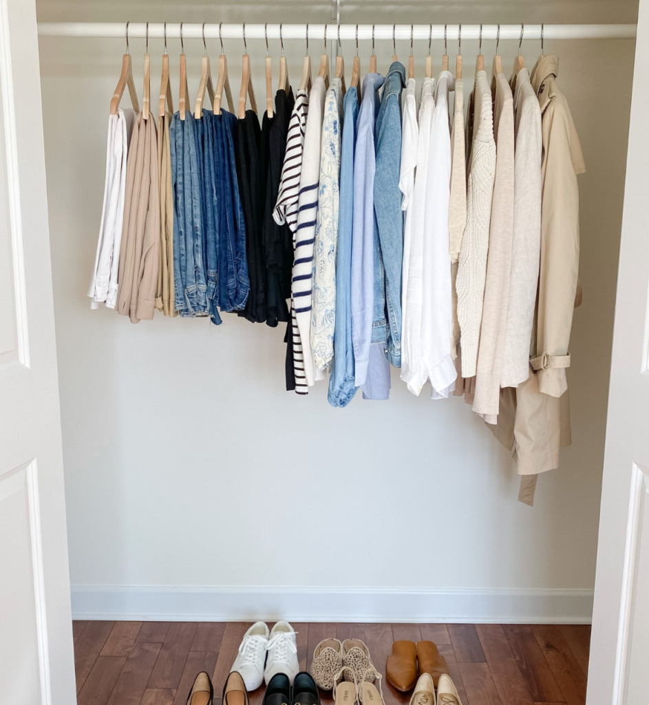Neatly arranged closet with color-coordinated clothes on wooden hangers and shoe storage below
