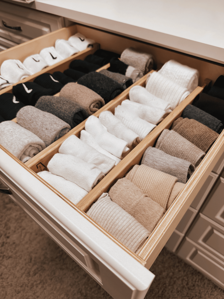 Sock organizer drawer with rolled socks sorted by color using wooden dividers