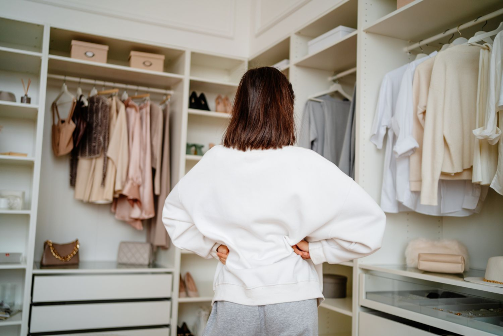 Modern walk-in closet with white shelving, hanging clothes, storage boxes, and minimalist wardrobe organization