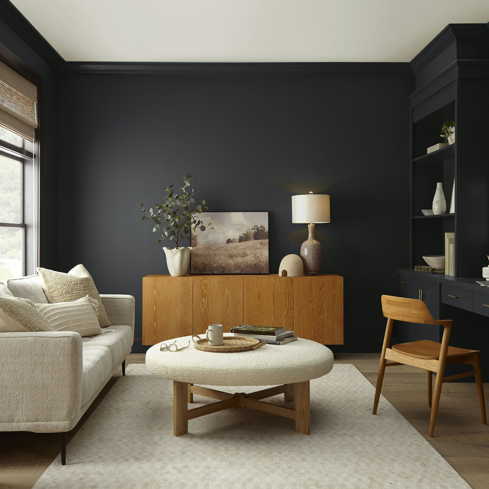 Modern living room with dark accent wall, wooden sideboard, round coffee table, and cozy neutral sofa decor
