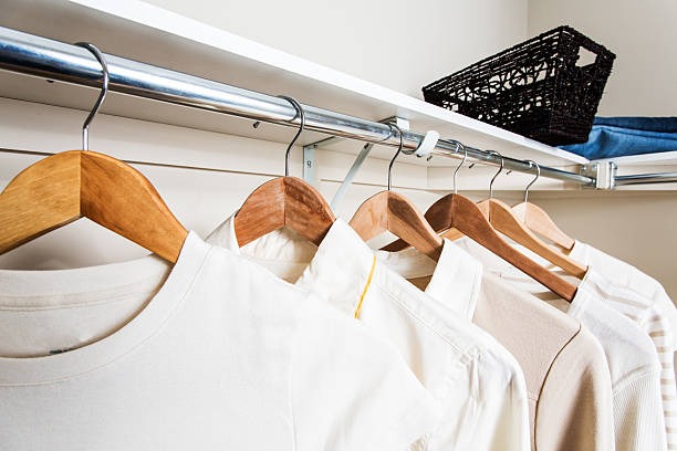 Neatly arranged shirts on wooden hangers inside a modern closet system