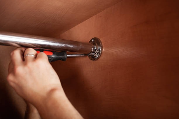 Installing a metal closet rod using a screwdriver for wardrobe storage setup