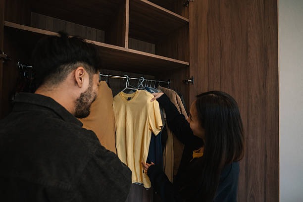 Couple organizing clothes together inside a wooden wardrobe closet