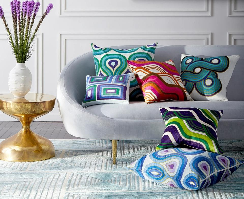Modern sofa styled with colorful geometric throw pillows and gold side table in a bright, contemporary living room