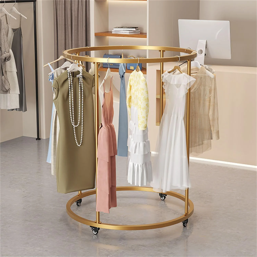 Round gold clothing rack on wheels displaying dresses and outfits in a modern boutique-style interior