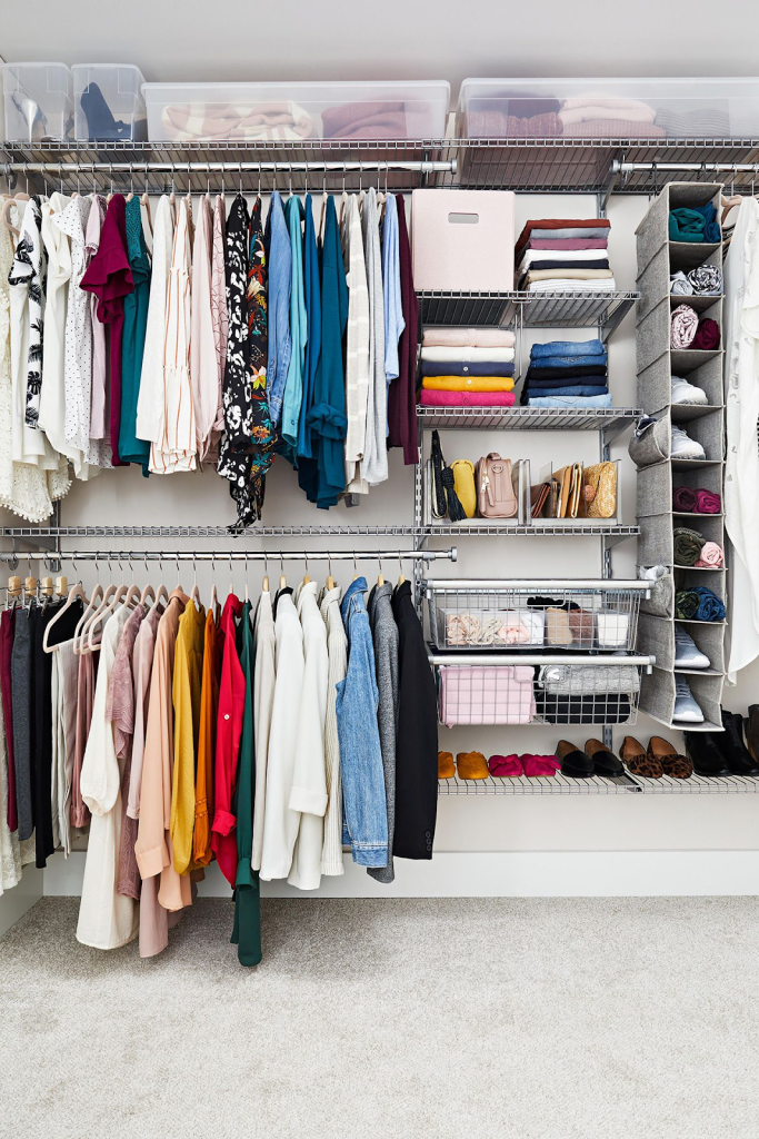 Well-organized walk-in closet with hanging clothes, folded sweaters, storage baskets, and neatly arranged shoes