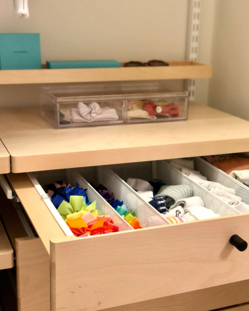 Clear drawer organizer with mesh dividers sorting socks, accessories, and small clothing items in a wooden dresser