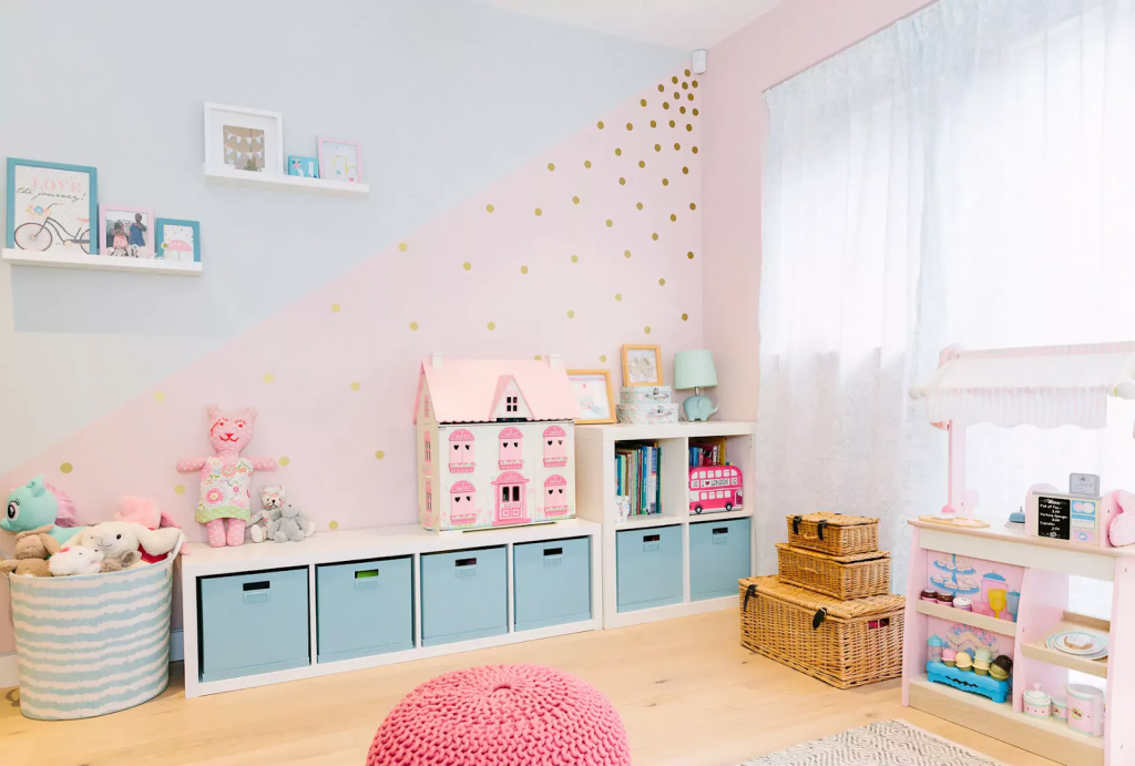 Pastel kids playroom with toy storage cubes, dollhouse shelf, woven baskets, and soft seating for organized and playful decor