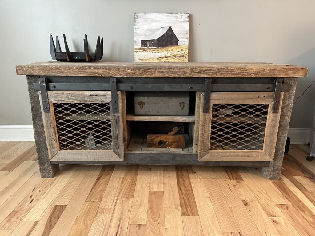 Rustic wooden media console with sliding barn-style doors and mesh panels in a living room