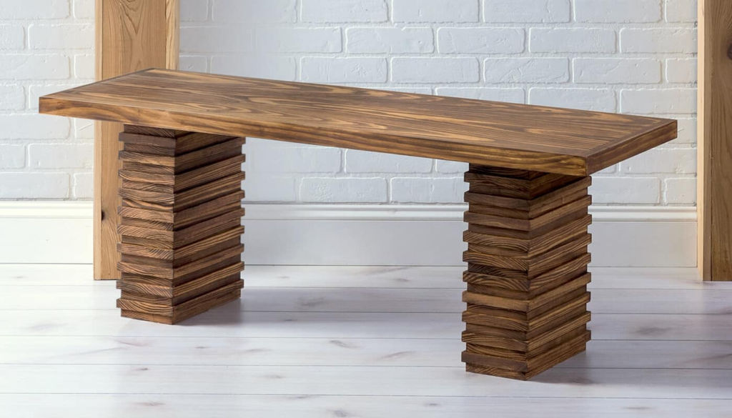Modern solid wood bench with stacked block legs and smooth finished tabletop in a minimalist interior