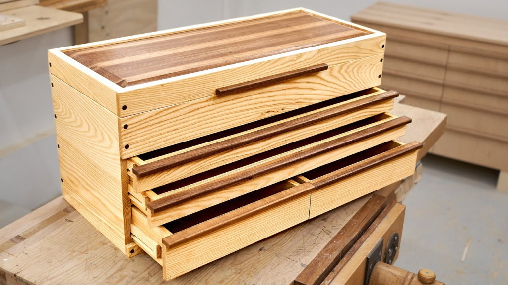 Handcrafted wooden drawer storage box with multiple sliding compartments on a woodworking bench
