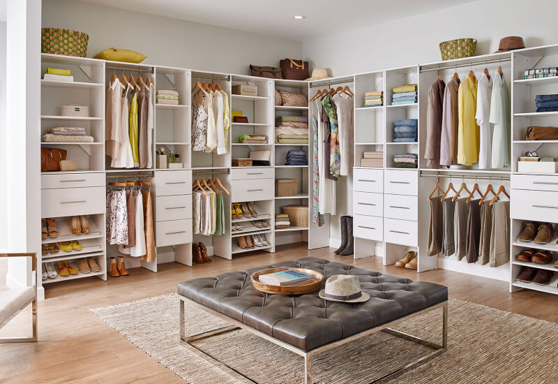Spacious walk-in closet with custom shelving, hanging racks, drawers, and seating bench