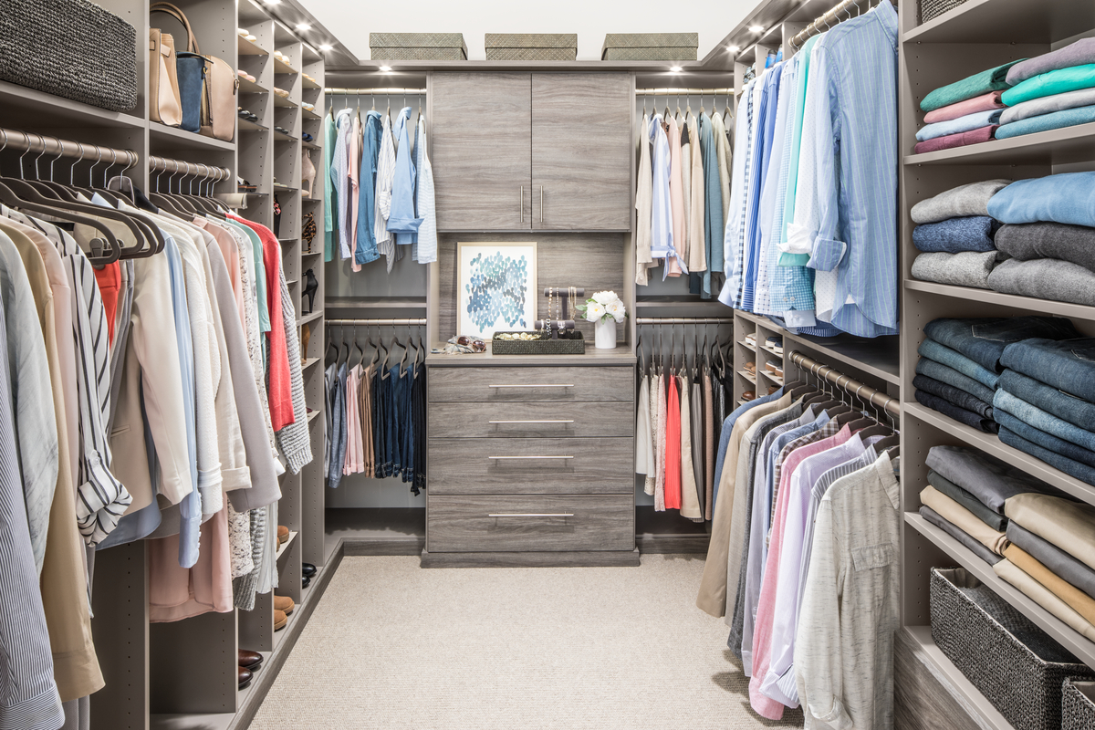 Modern walk-in closet with built-in shelves, hanging clothes, and central drawer storage system