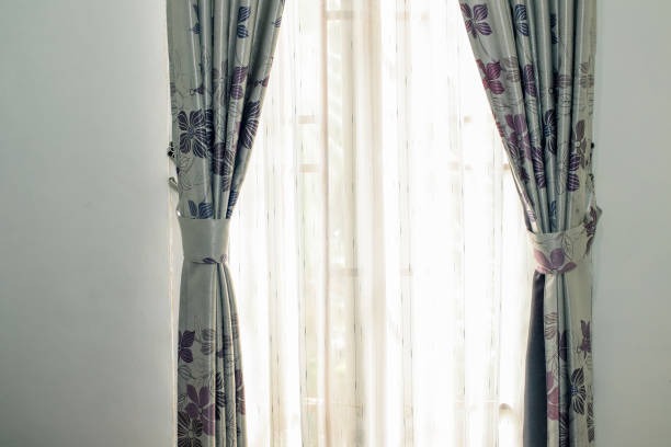 Light gray floral curtains with tiebacks framing a bright window