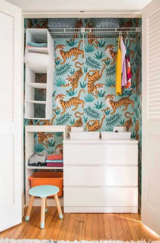 Small closet organization idea with shelves, drawers, hanging rod, and decorative wallpaper