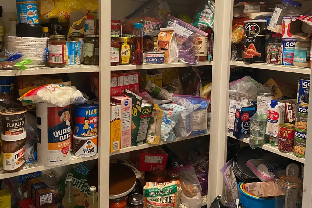 Cluttered pantry shelves filled with groceries, canned food, and dry goods before kitchen organization