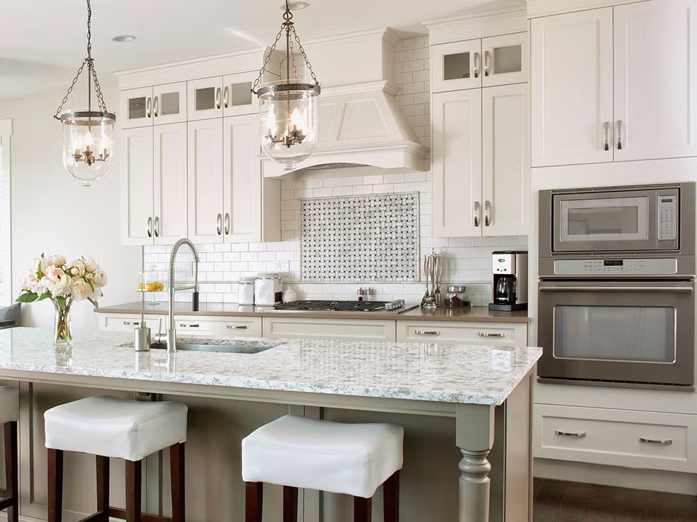 Elegant white kitchen with marble island, pendant lights, and built-in appliances in a modern home