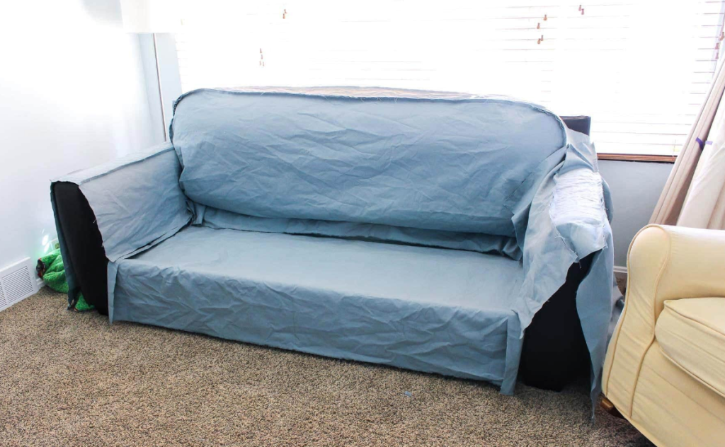 Light blue sofa with fitted slipcover placed in bright living room near window