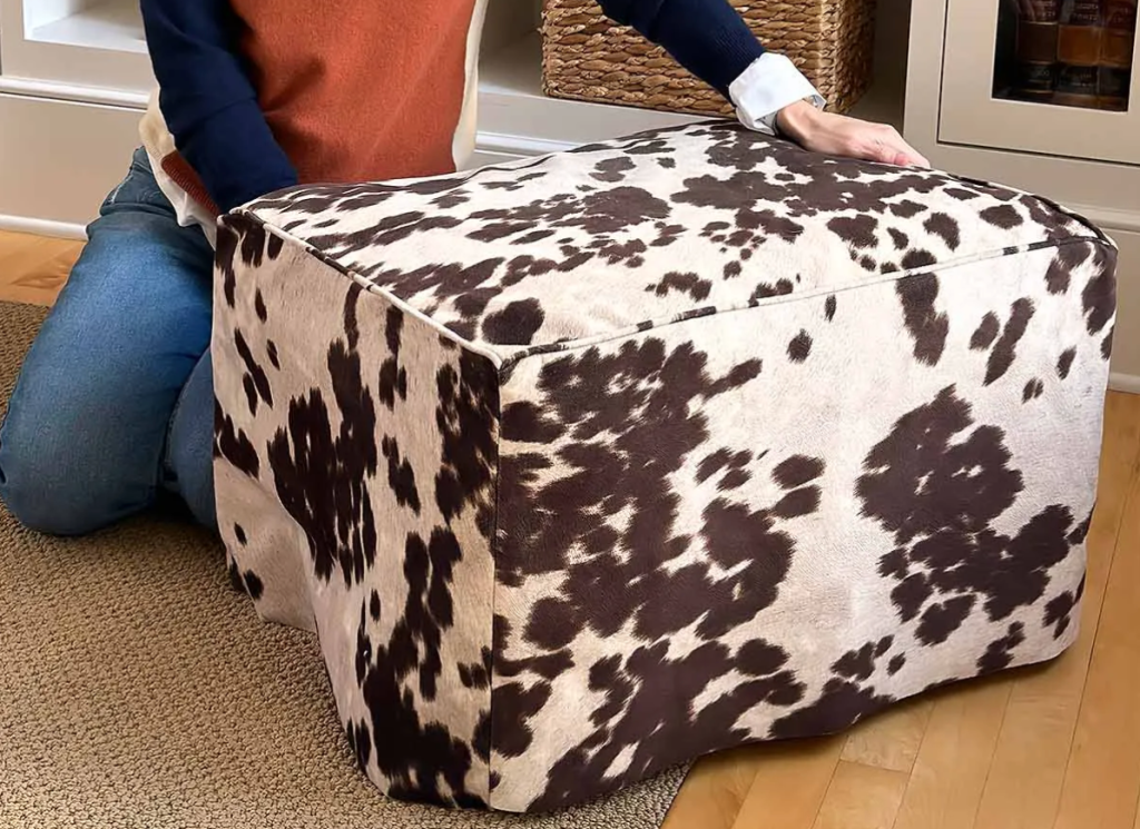 Cow print cube ottoman used as decorative footstool in cozy living room