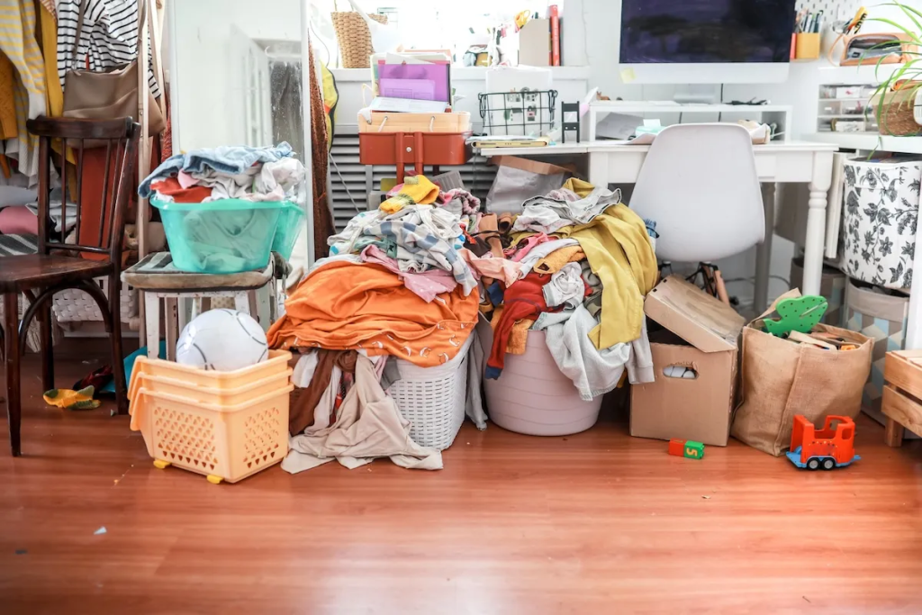 messy room with piles of clothes and clutter before home decluttering and organization
