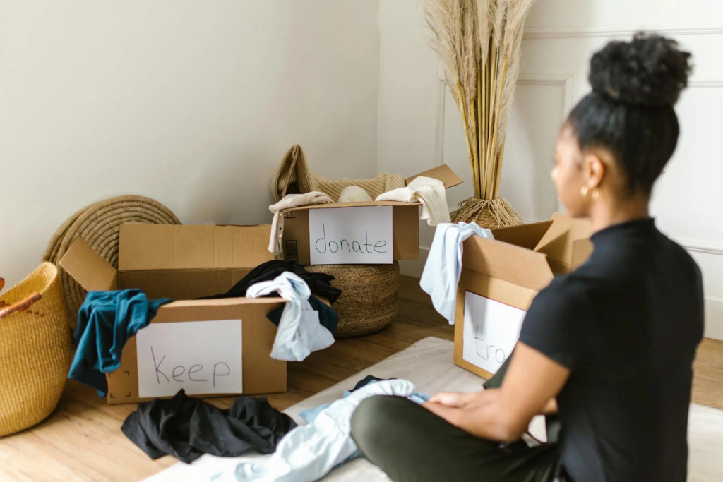woman sorting clothes into keep and donate boxes during home decluttering