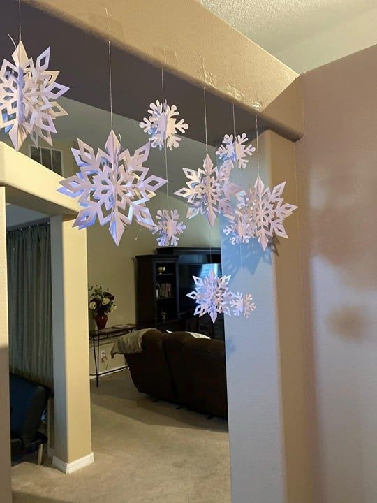 DIY paper snowflake decorations hanging in doorway for winter home decor