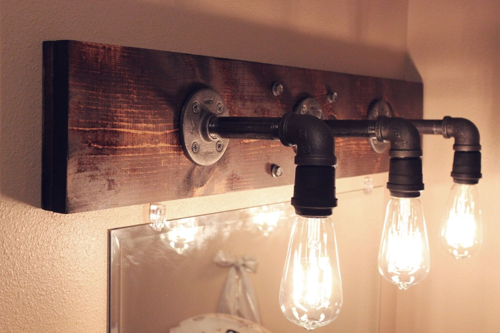 DIY industrial pipe light fixture with Edison bulbs mounted on rustic wood board