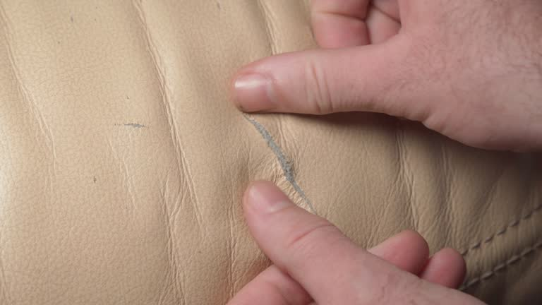 close up of cracked and torn beige leather upholstery needing repair on furniture seat