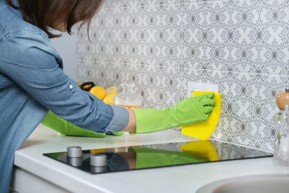 cleaning kitchen backsplash tiles with cloth and gloves for stain removal