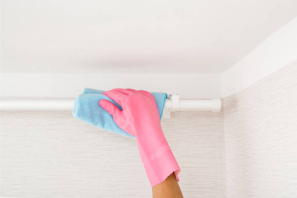 cleaning curtain rod with microfiber cloth and gloves for home maintenance