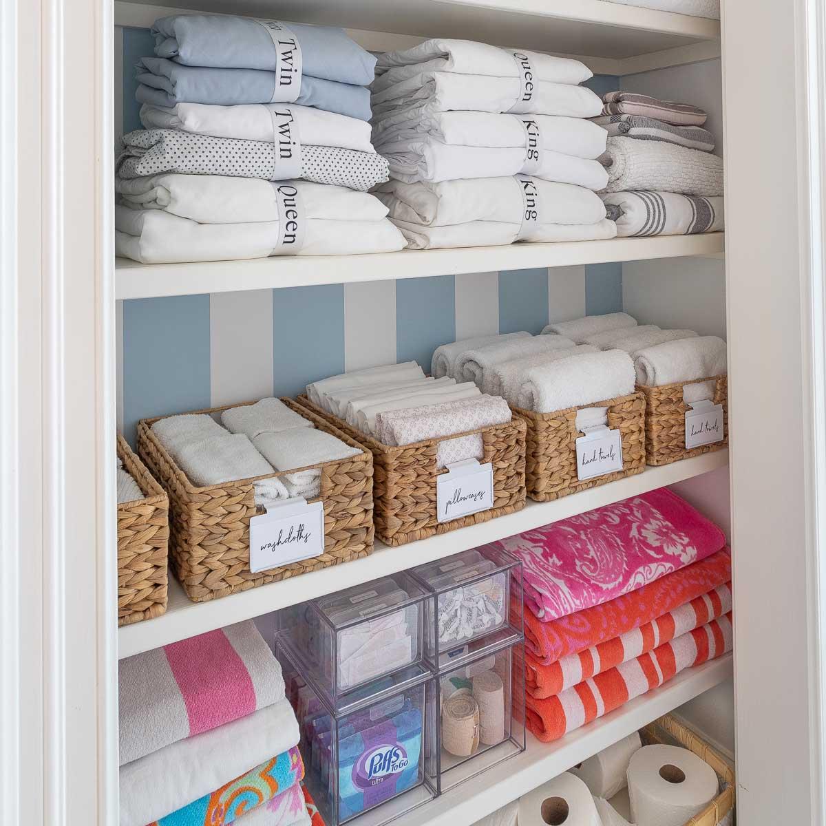 Organized linen closet with labeled baskets and towels
