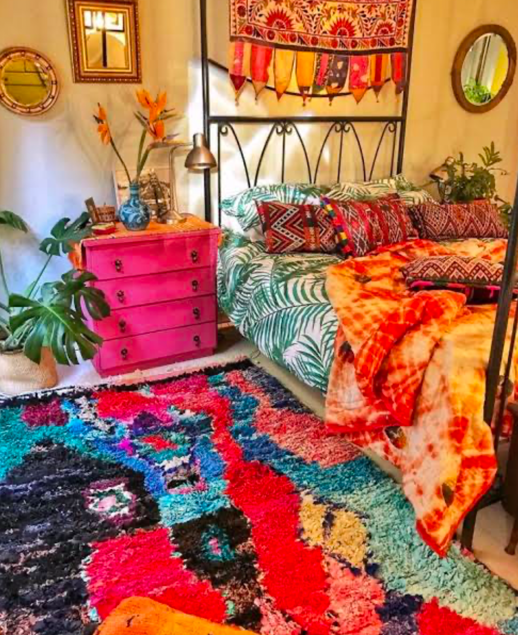 Vibrant boho bedroom with a pink dresser and bold rug