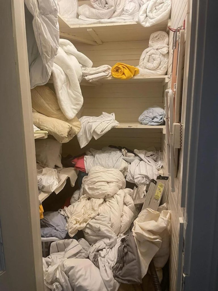 Messy linen closet with overflowing bedding