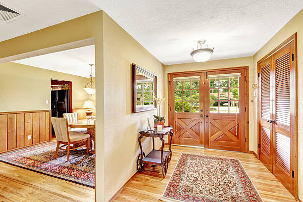 Bright entryway with wooden floors, double front doors, and area rugs