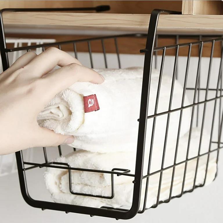 Hand placing rolled towel into wire storage basket