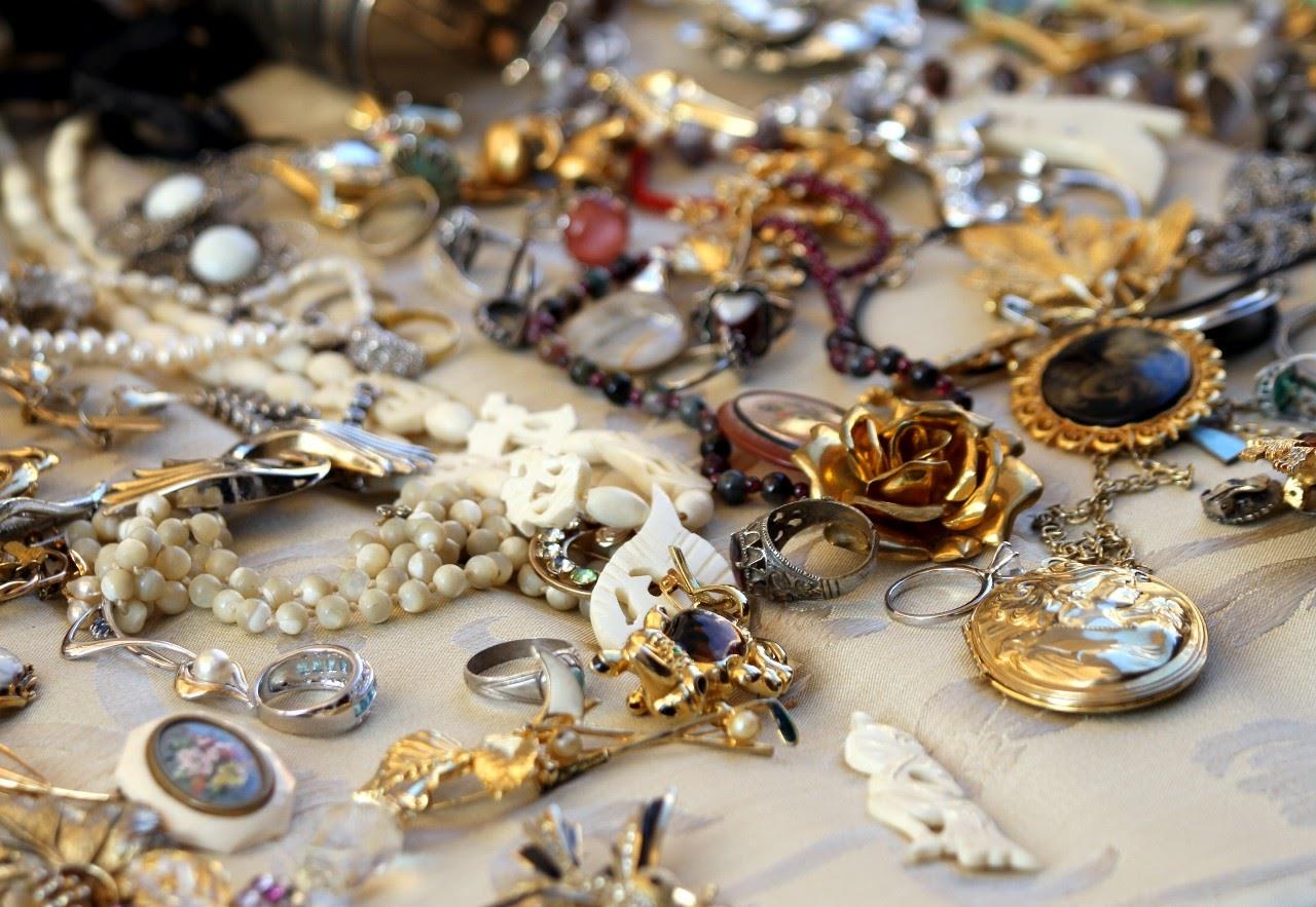 Collection of assorted vintage jewelry on a beige surface