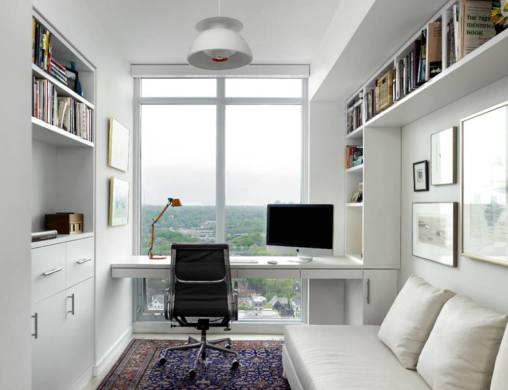 Minimalist home office with large window, black chair, and built-in shelves.